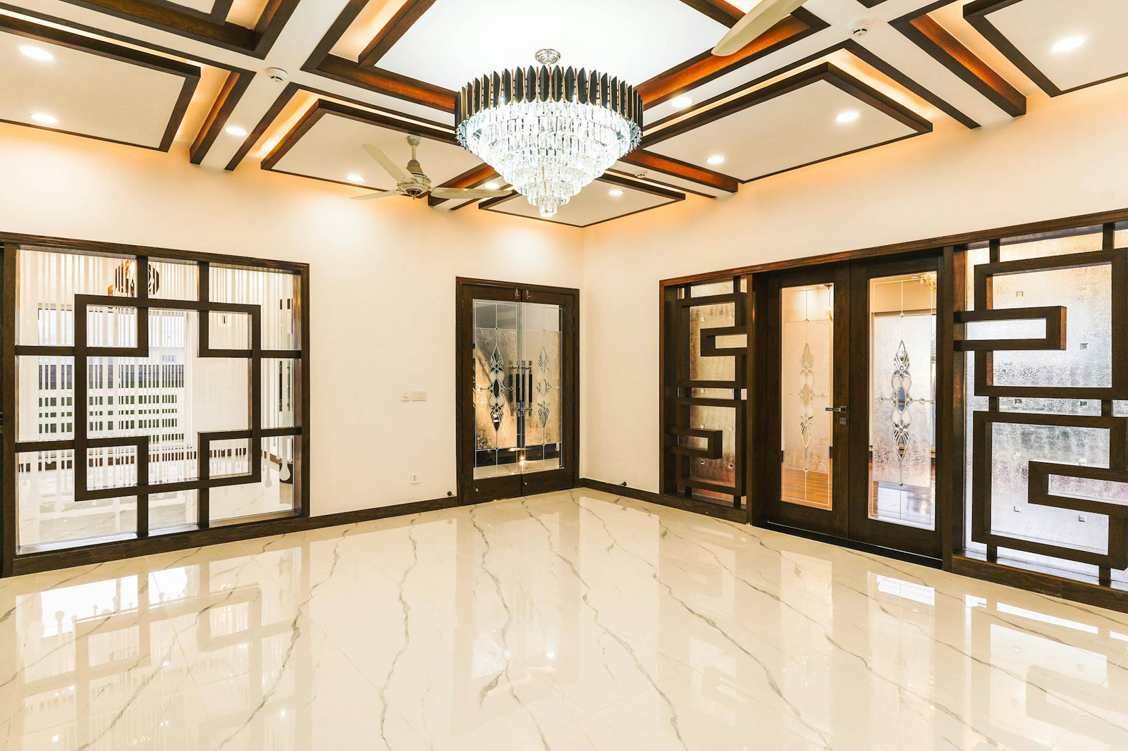 Luxurious interior with a stunning chandelier, intricate woodwork, and polished marble flooring.
